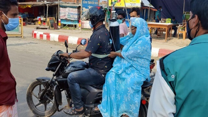 মোটরসাইকেলে ছেলের পিঠে বাঁধা সিলিন্ডার থেকে অক্সিজেন নিচ্ছেন মা রেহানা পারভিন  